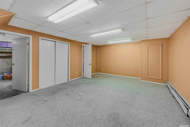 basement with a drop ceiling, carpet, and a baseboard radiator