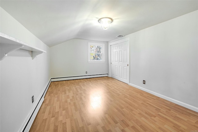 additional living space with a baseboard radiator, lofted ceiling, and light wood-type flooring