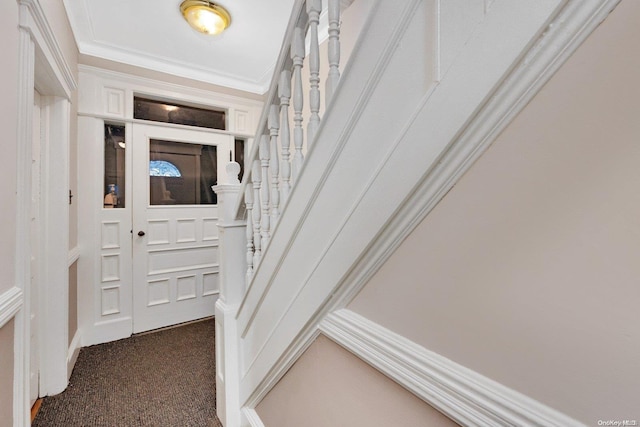 foyer entrance featuring dark carpet and ornamental molding