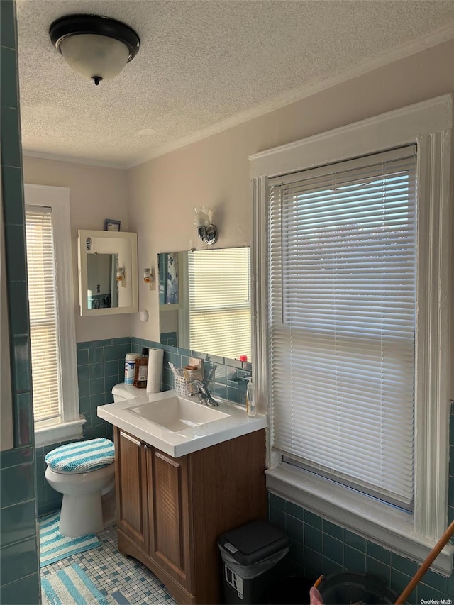 bathroom featuring vanity, tile patterned flooring, toilet, tile walls, and a textured ceiling