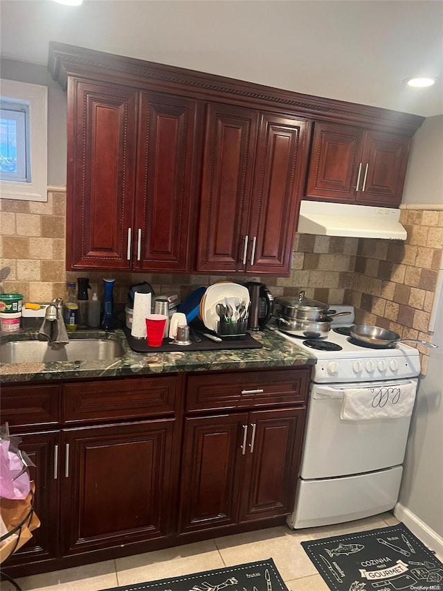 kitchen featuring sink, backsplash, dark stone counters, light tile patterned floors, and white stove