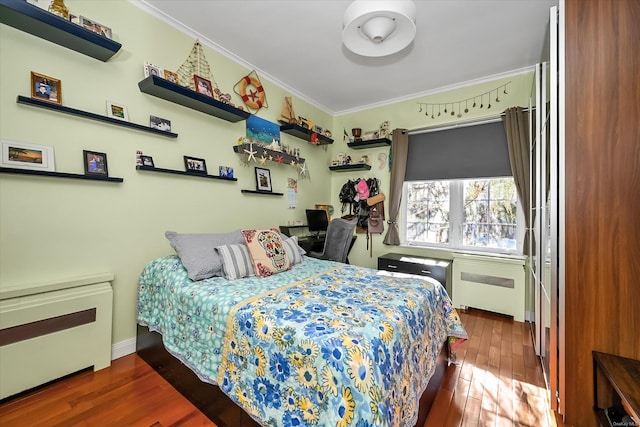 bedroom featuring radiator, wood finished floors, and crown molding