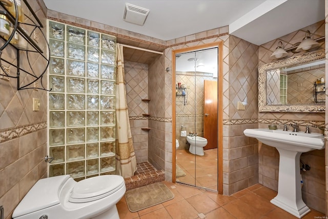 bathroom featuring visible vents, toilet, tile patterned floors, a shower stall, and tile walls