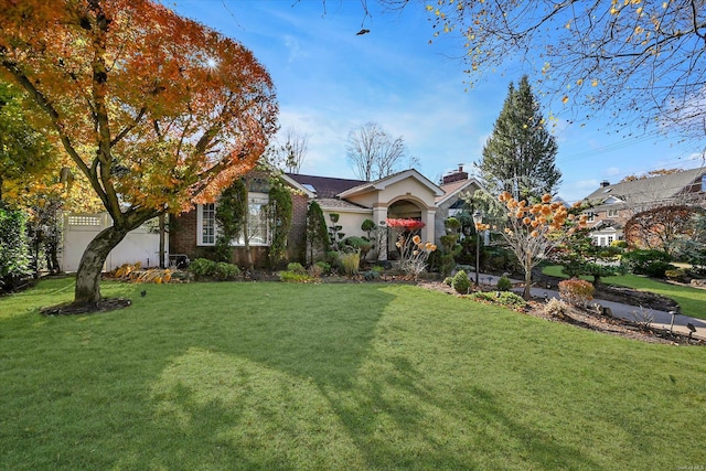 view of front of house with brick siding, a chimney, and a front yard