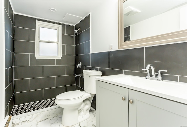 bathroom with tiled shower, vanity, toilet, and tile walls