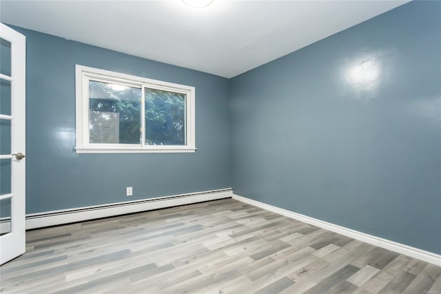 spare room with baseboard heating and light hardwood / wood-style flooring