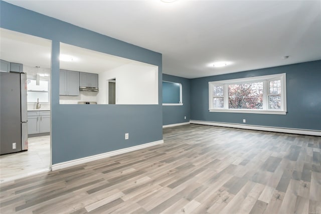 spare room featuring light wood-type flooring, sink, and a baseboard heating unit