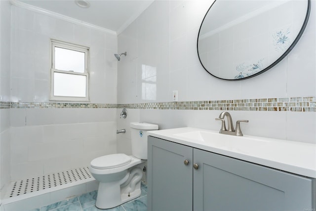 bathroom with ornamental molding, a tile shower, vanity, tile walls, and toilet