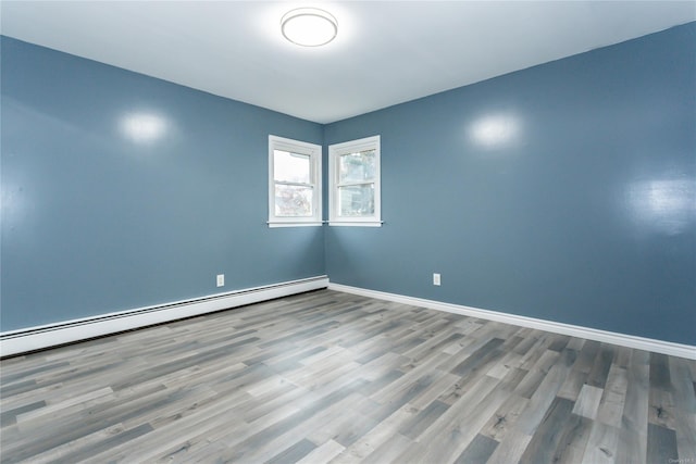 spare room featuring wood-type flooring and a baseboard radiator