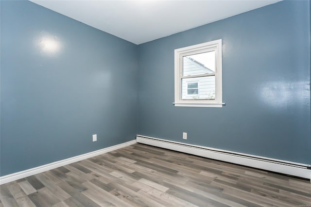 unfurnished room featuring hardwood / wood-style floors and a baseboard radiator