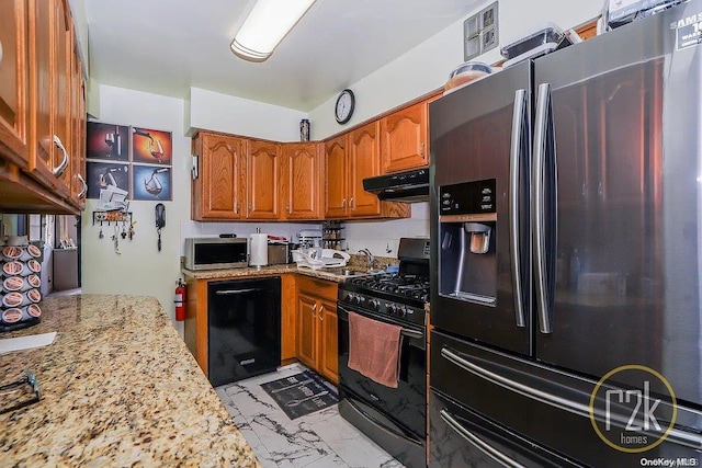 kitchen with light stone countertops, sink, and black appliances