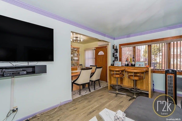 interior space featuring a chandelier, hardwood / wood-style floors, a wall unit AC, and crown molding