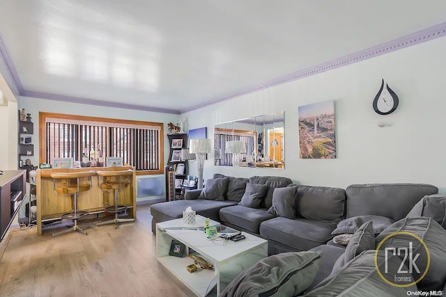 living room featuring bar area, light wood-type flooring, and crown molding