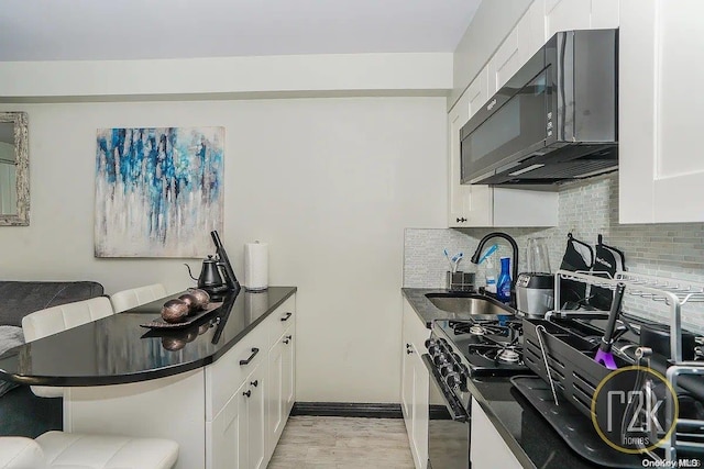 kitchen featuring sink, white cabinets, and stainless steel range oven