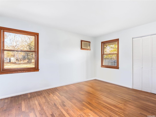 empty room featuring hardwood / wood-style flooring and a wall unit AC