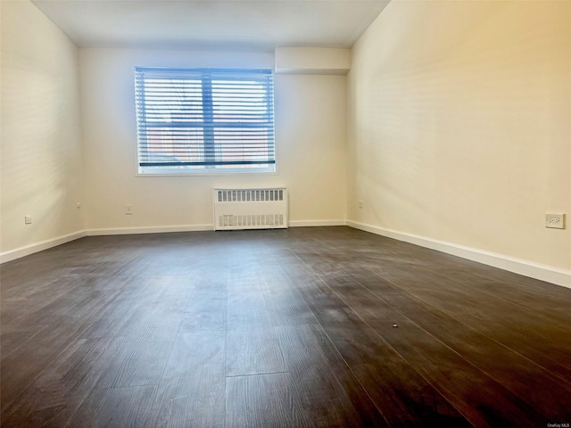 unfurnished room with dark hardwood / wood-style flooring and radiator heating unit