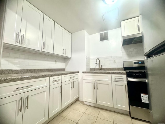 kitchen with appliances with stainless steel finishes, sink, white cabinets, exhaust hood, and light tile patterned floors