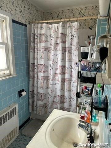 bathroom featuring radiator and tile walls