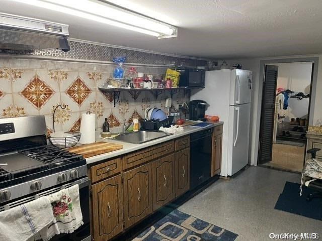 kitchen with dishwasher, stainless steel range with gas cooktop, sink, wall chimney range hood, and dark brown cabinetry