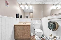 bathroom featuring a paneled ceiling, sink, tile walls, and toilet