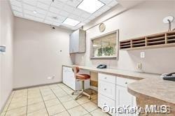 kitchen featuring light tile patterned floors, built in desk, white cabinetry, and a paneled ceiling