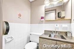 bathroom with vanity, toilet, and tile walls