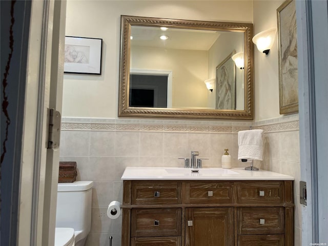 bathroom with vanity, toilet, and tile walls