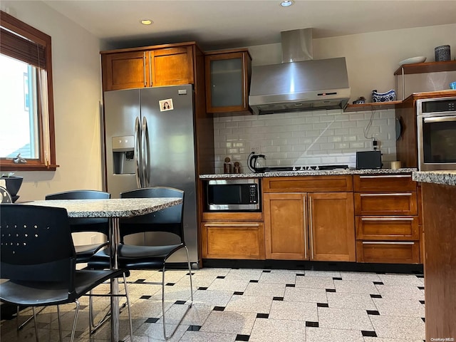 kitchen with backsplash, stainless steel appliances, and wall chimney range hood