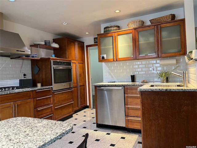 kitchen featuring wall chimney exhaust hood, sink, appliances with stainless steel finishes, and tasteful backsplash