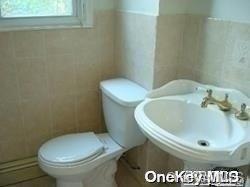 bathroom featuring toilet, tile walls, and sink