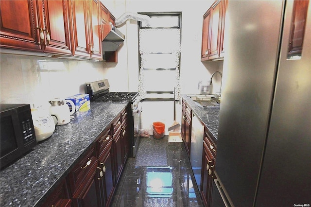 kitchen featuring sink, dark tile patterned floors, dark stone counters, and appliances with stainless steel finishes