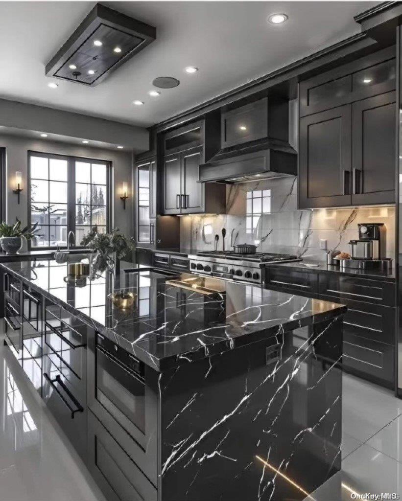 kitchen with premium range hood, tasteful backsplash, light tile patterned floors, dark stone countertops, and a center island