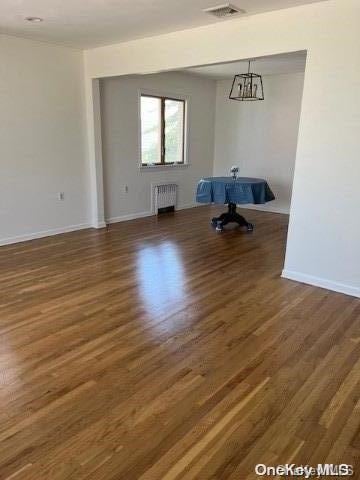 interior space featuring dark hardwood / wood-style flooring, radiator heating unit, and an inviting chandelier