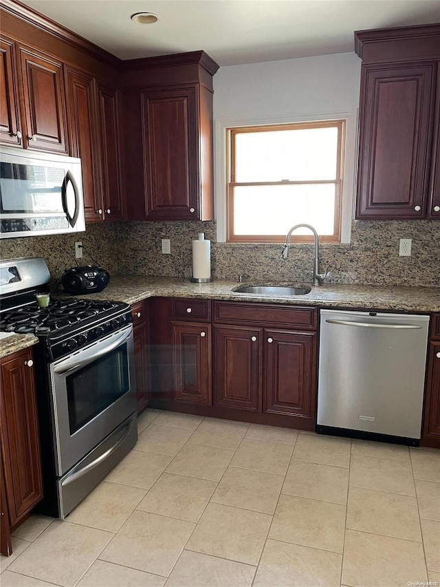 kitchen with stone counters, decorative backsplash, sink, and stainless steel appliances