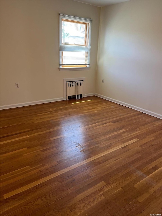 unfurnished room with dark hardwood / wood-style flooring and radiator