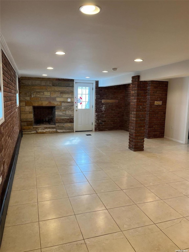 unfurnished living room featuring a fireplace, light tile patterned floors, brick wall, and a baseboard heating unit