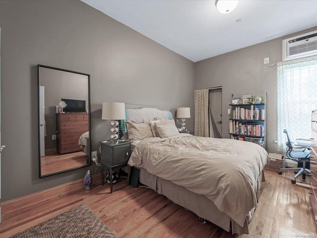 bedroom with wood-type flooring and an AC wall unit