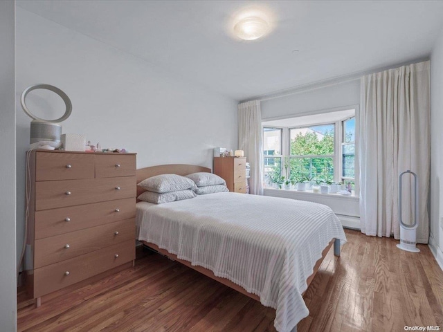 bedroom featuring hardwood / wood-style floors and a baseboard heating unit