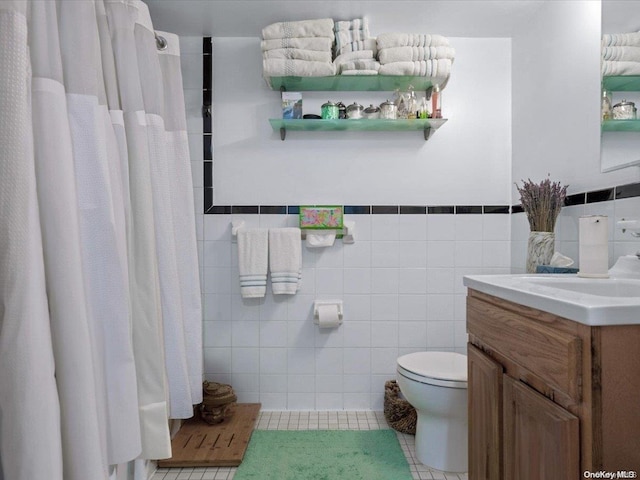 bathroom with tile patterned floors, vanity, toilet, and tile walls