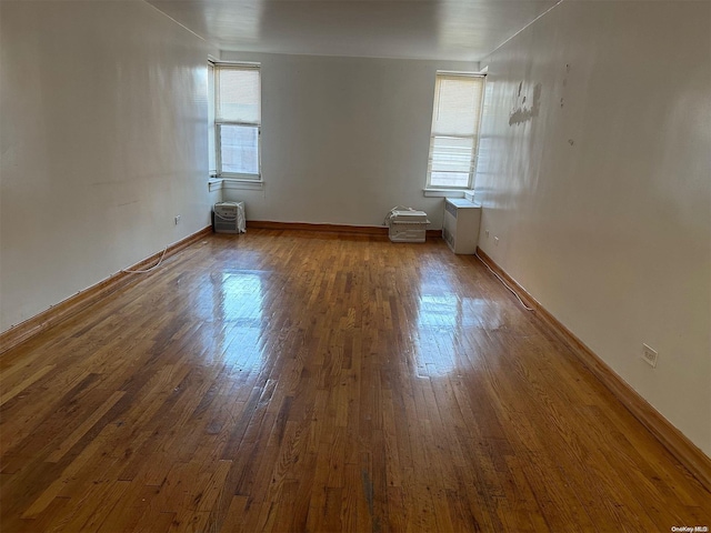 unfurnished room with a wall mounted AC and dark hardwood / wood-style floors