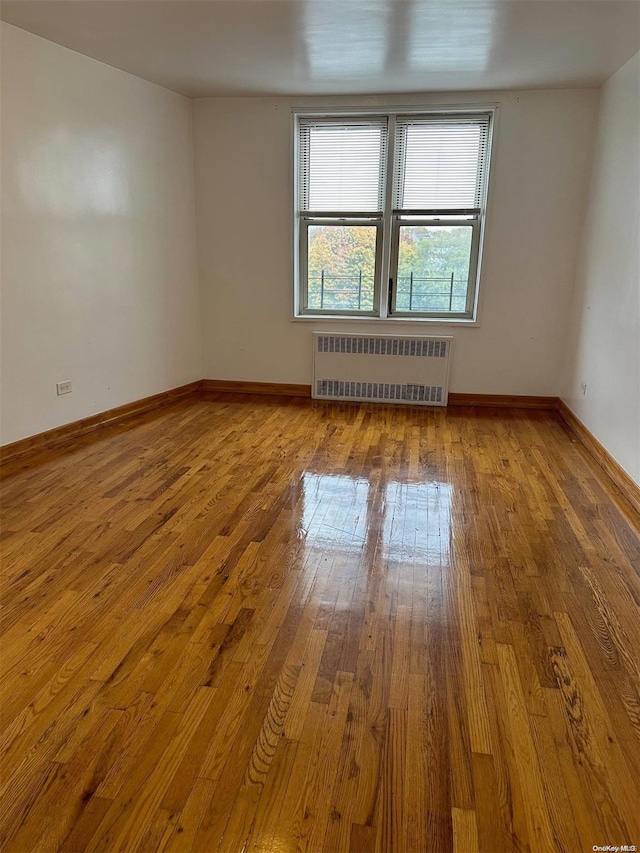 empty room featuring radiator and light hardwood / wood-style flooring