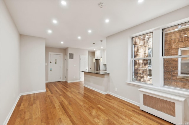 unfurnished living room with radiator and light hardwood / wood-style flooring