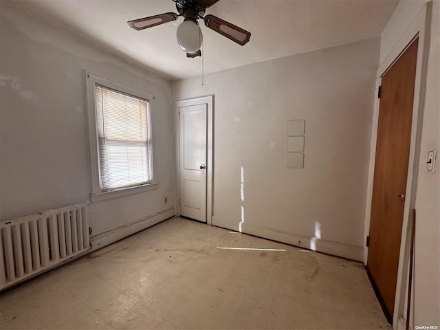 unfurnished room featuring ceiling fan and radiator