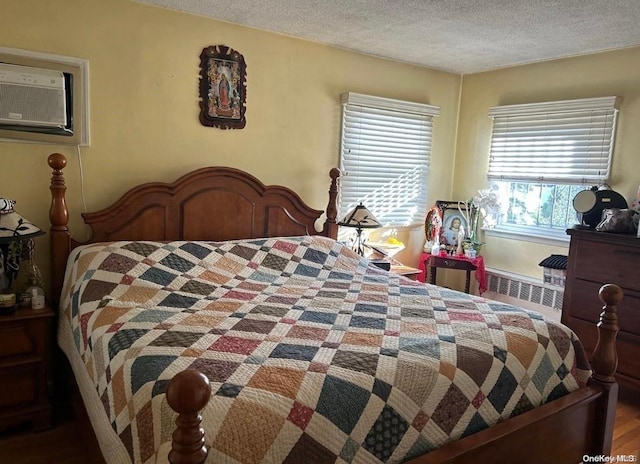 bedroom featuring multiple windows, radiator heating unit, hardwood / wood-style floors, and a textured ceiling