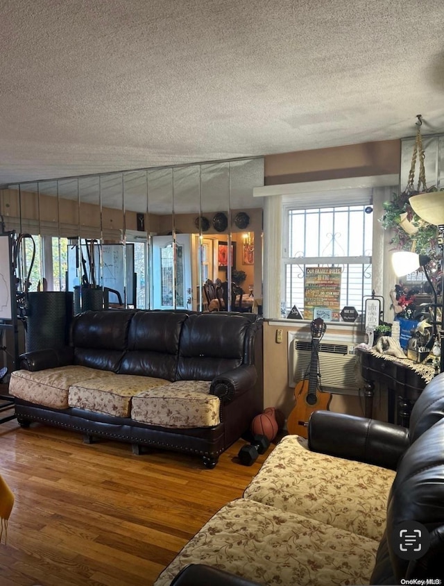 living room featuring wood-type flooring, a textured ceiling, and an AC wall unit