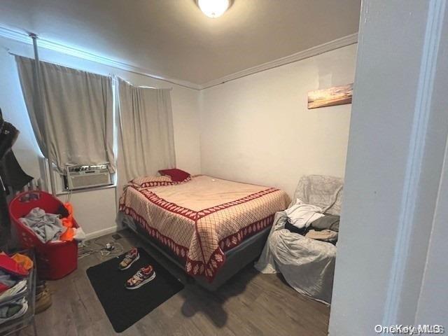 bedroom with hardwood / wood-style floors, cooling unit, and ornamental molding