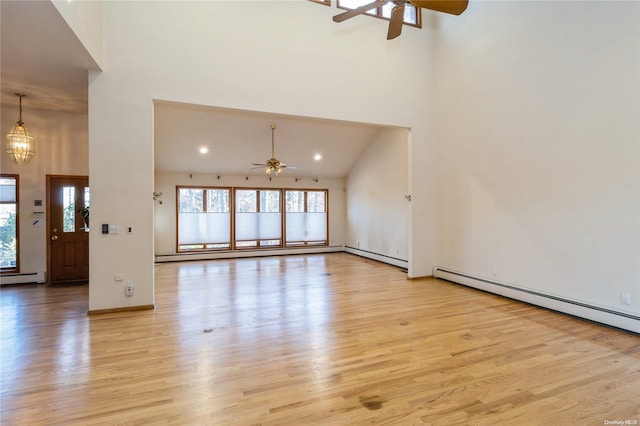 unfurnished living room featuring high vaulted ceiling, light hardwood / wood-style floors, and ceiling fan with notable chandelier