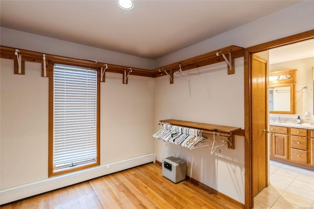 spacious closet with sink, light wood-type flooring, and a baseboard heating unit