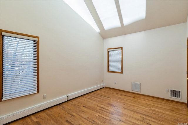 unfurnished room with lofted ceiling, light hardwood / wood-style flooring, and a baseboard heating unit