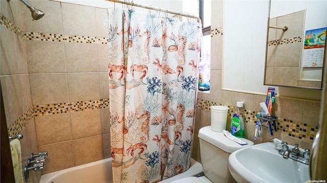 full bath with tile walls, shower / tub combo, toilet, and a sink